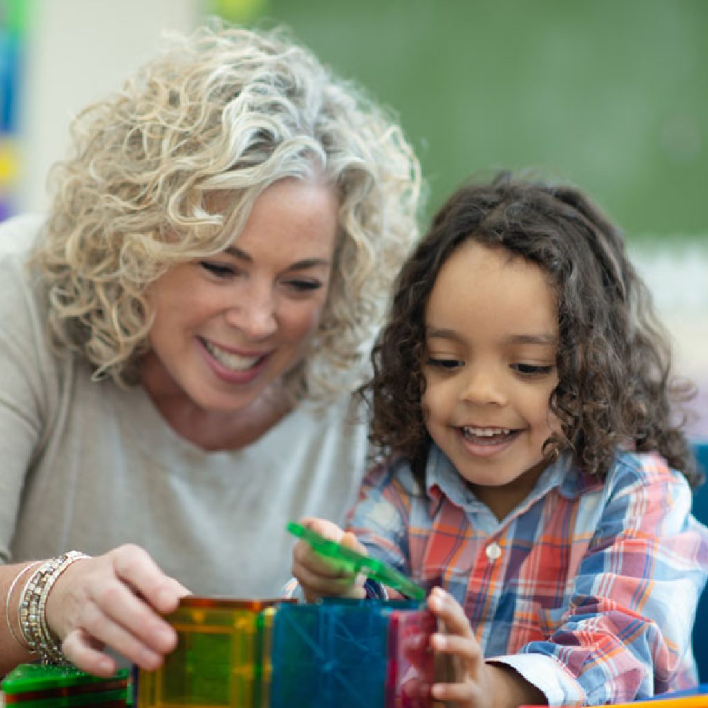 Teacher at Discovery Corner Academy helping child with building blocks