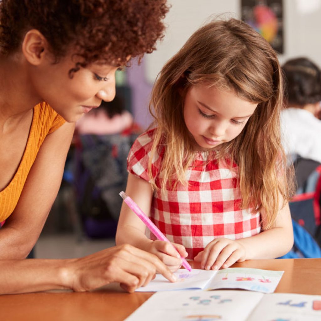 Child coloring with teacher in a pre-kindergarten class at Discovery Corner Academy